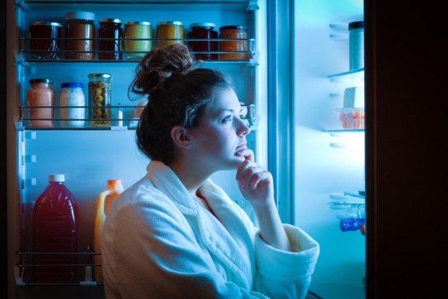 Woman staring at open fridge