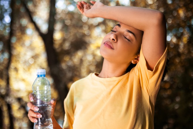 Woman drinking water outside in the heat