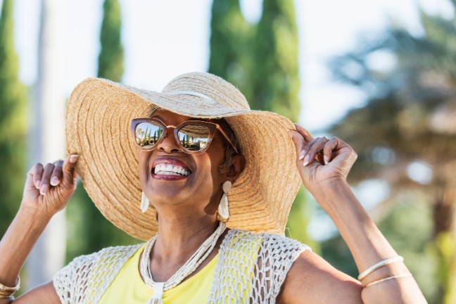 Woman with cancer outside while wearing a sun hat