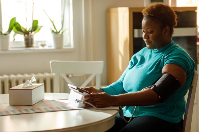 Black woman taking her blood pressure at home