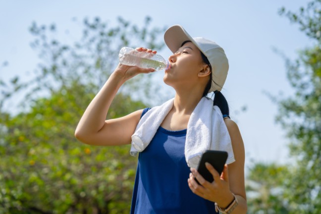 Young athlete drinking water outside in the heat