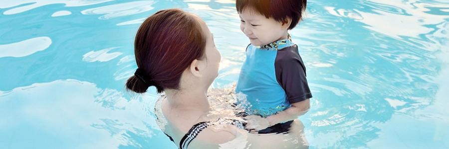 A mother and her toddler son swim in a pool together